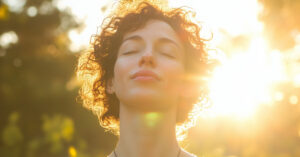 A young woman practices spiritual concepts like prayer. Her eyes are close, she draws in energy from nature.