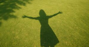 shadow of a woman with arms outstretched in sunlight, symbolizing personal empowerment and joy