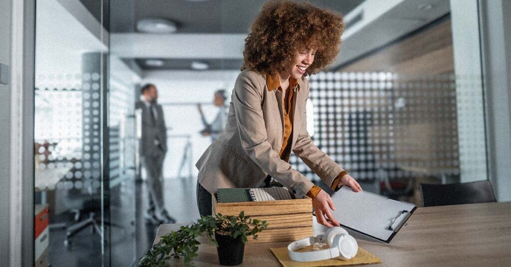 Confident woman smiling while organizing desk in modern office, embracing a fresh start